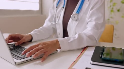 Unrecognizable Female Doctor Working on Laptop at Medical Office