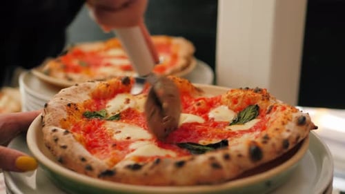 Woman Cutting Fresh Pizza with Pizza Cutter Indoors