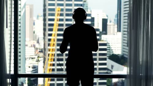 Silhouette of Man Dancing to Music in Apartment