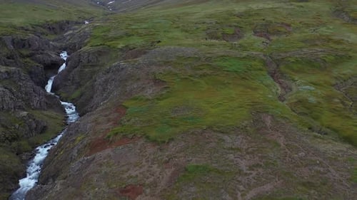 Beautiful Small Waterfall Flowing Through Green Rocky Moss Covered Hills