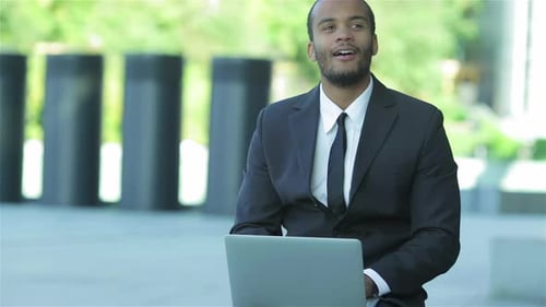 Man In Suit Works On Laptop Outdoors