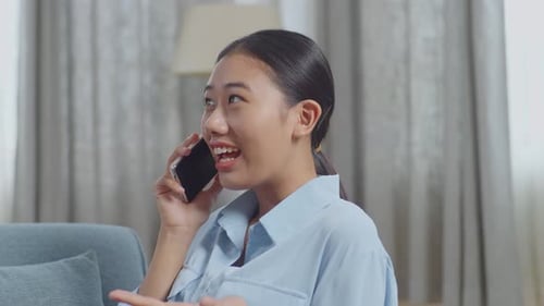 Close Up Of Asian Woman Talking On Smartphone While Lying On Sofa In The Living Room