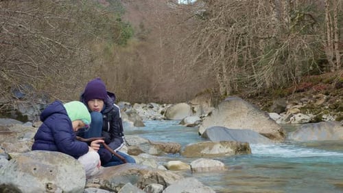 Crianças explorando à beira do rio