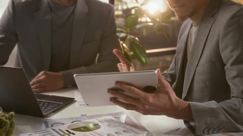 Men Discuss Business Analytics Using Tablet and Laptop