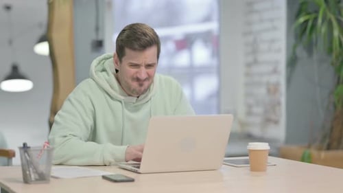 Young Man Reacting to Loss While Working in Office