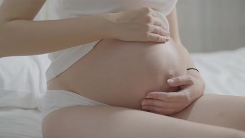 беременная гладит свой живот, крупный план груди