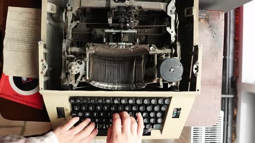 Vue aérienne d'une personne tapant sur une ancienne machine à écrire manuelle. Angle élevé