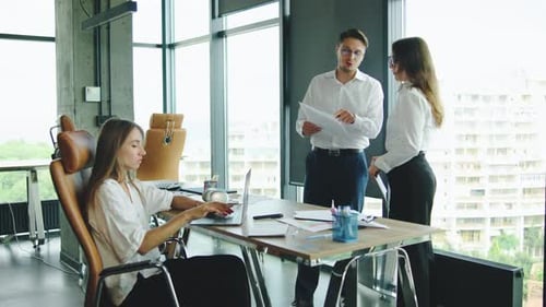 In a Modern Office a Man Argues with a Woman Over Documents While Another Colleague Stands Up From