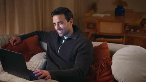 Man Relaxes on Sofa Using Laptop