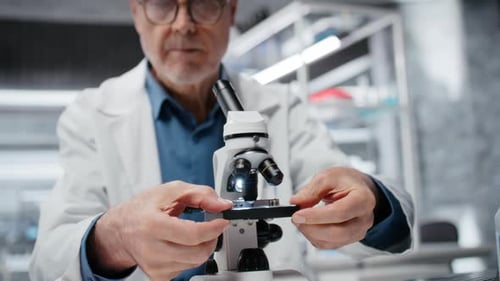 Male Scientist Adjusting Microscope in Modern Laboratory