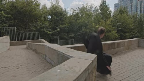 Athletic Person Jumps Over Wall in Park Setting