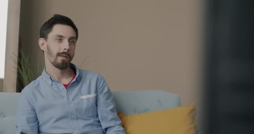 Man Relaxes and Smiles While Watching Television