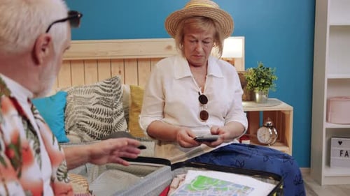 Close Up Grandfather and Grandmother Couple in Bedroom Packing Suitcase for Vacation Clothing