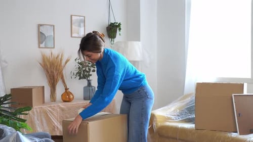 Woman Packs Belongings in Cardboard Box for Moving