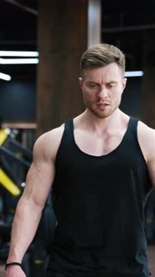 Esportista cansado descansa após um treino intenso. Homem musculoso em camiseta preta em um moderno centro de fitness
.