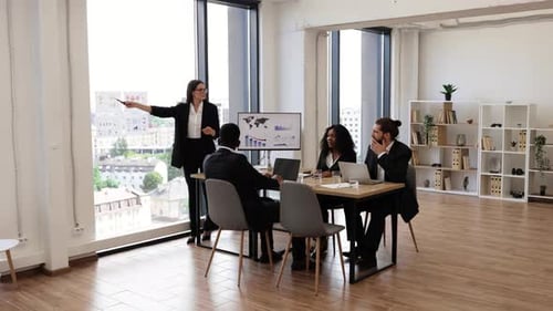 Business Woman Presenting Report to Multiracial Colleagues in Modern Office