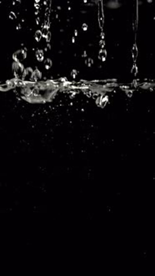 Water Droplets Splashing into Water on Black Background