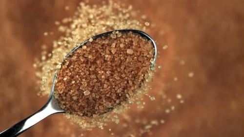 Brown Sugar on Spoon Close Up with Brown Background