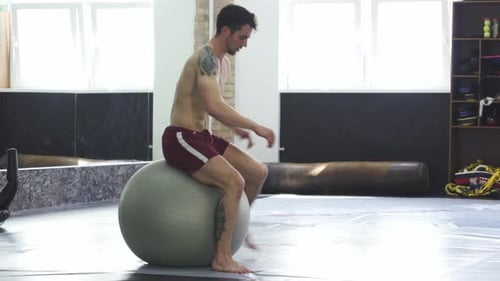Athletischer junger Mann balanciert gekonnt auf einem Fitnessball