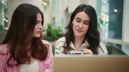 Women Discussing Over a Smartphone in a Cafe