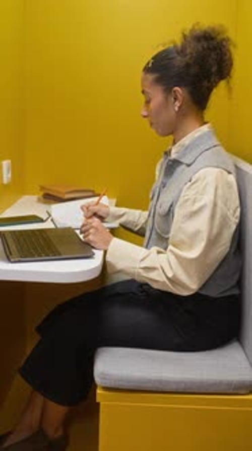 Focused Biracial Student Girl Taking Notes while Working on Laptop in Library
