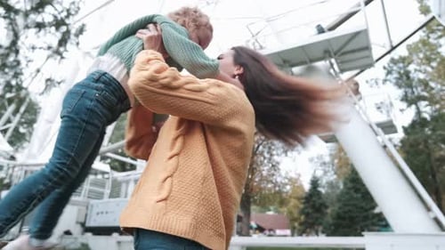 Loving mother walks with her cute daughter in the park. She is holding her daughter in her arms. Nea
