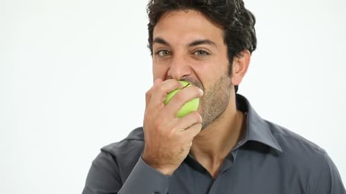 Young Man Eating Green Apple Isolated on White Background. Smiling Guy Bitten
