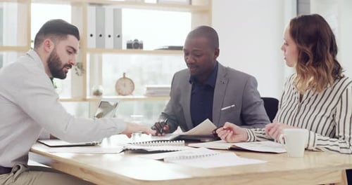 4k video footage of a group of businesspeople going through paperwork together in an office