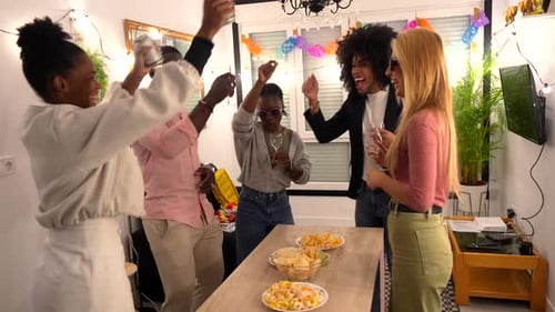 Amigos multiétnicos rindo e bebendo na festa em casa