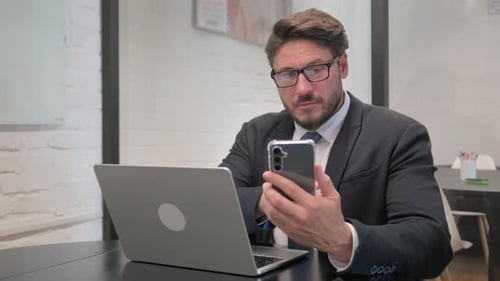 Man in Suit Working With Laptop and Phone