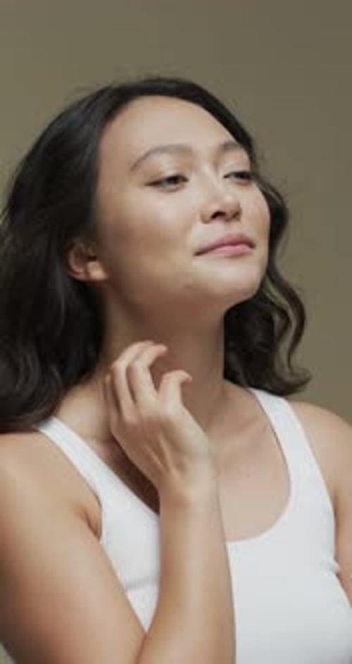 Young Woman Gently Touching Her Neck in Studio