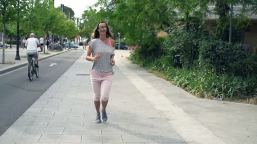 Attractive young woman jogging alone in the city in super slow motion