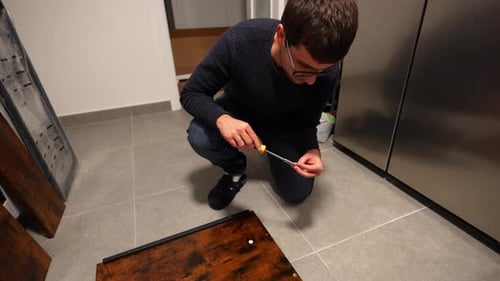 Man Assembling Furniture at Home with Screwdriver