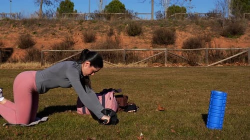 Woman exercising with an abdominal wheel in a park. Outdoor workout