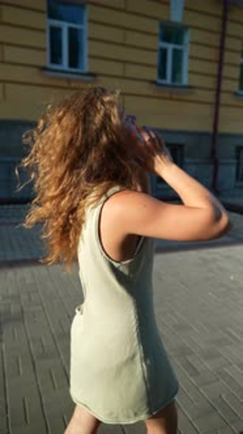Woman Walks Along Sunny City Sidewalk