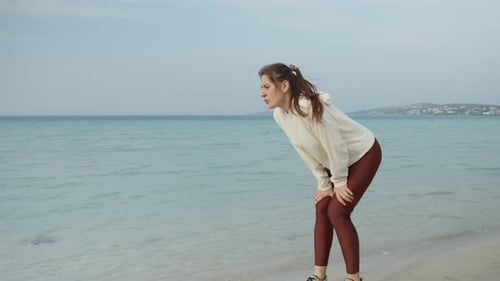 Slow motion of young woman runs on sandy sea beach, stops and takes a break