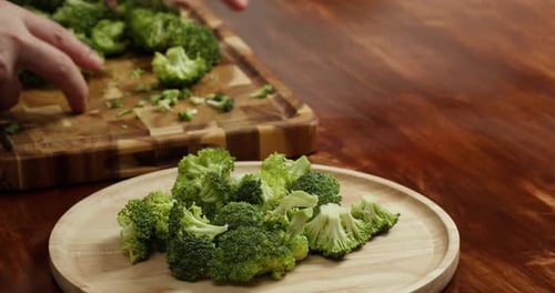 Closeup of Hands Cutting Fresh Broccoli on Wooden Board in Kitchen Healthy Vegan Cooking Fresh
