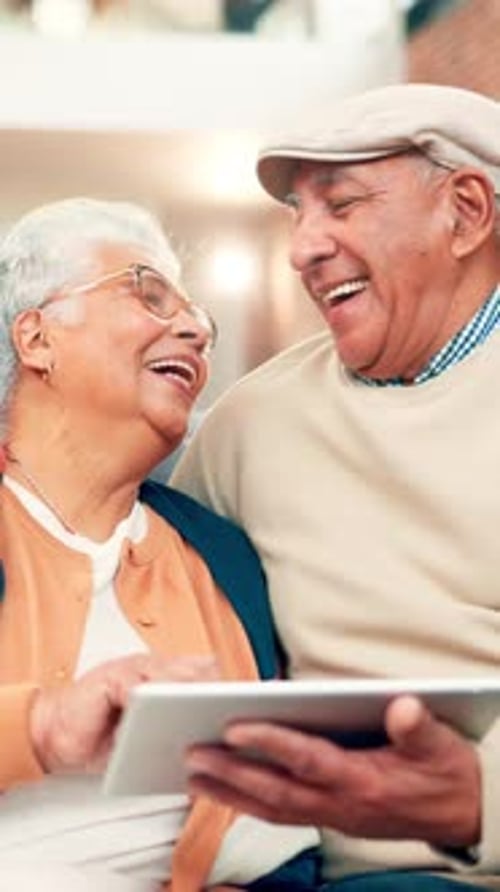 Happy senior couple laughing using a tablet device