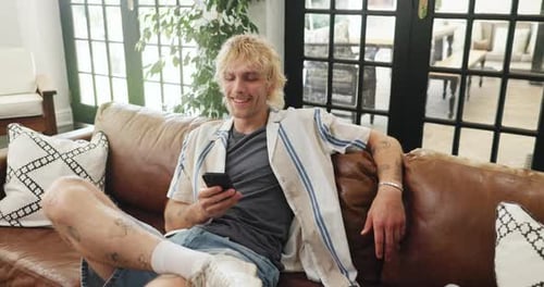Young Man Relaxing on Couch Using Cell Phone
