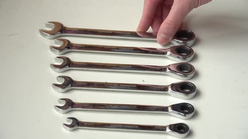 A man lays out wrenches of different sizes on the table, a tool for tightening nuts