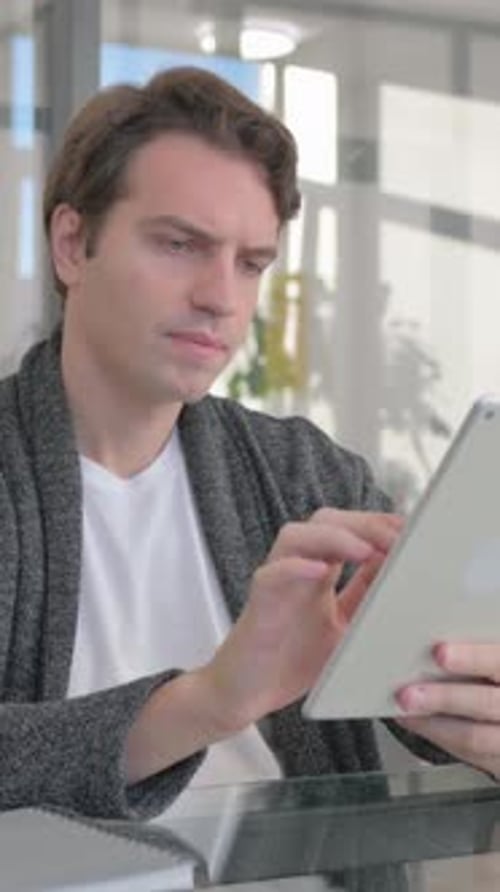 Young Man Using Digital Tablet in Office, vertical video