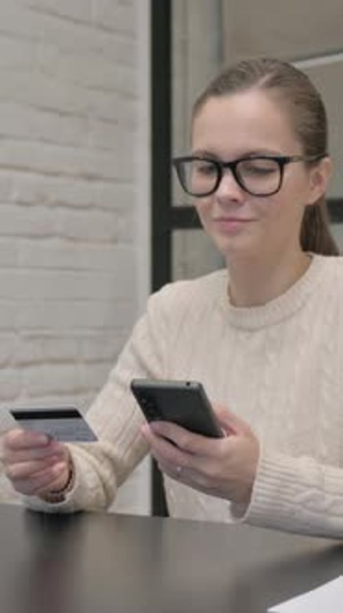 Woman using phone and credit card indoors