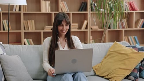 Woman Opens Laptop on Sofa at Home