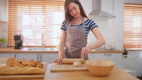 Woman Rolls Dough in Sunny Kitchen