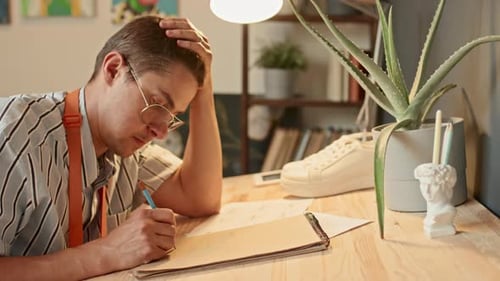Man Drawing in Sketchbook at Wooden Desk