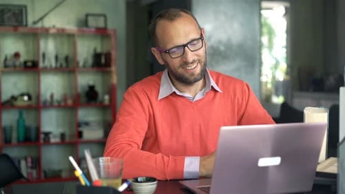 Man Speaking at Desk with Laptop at Home