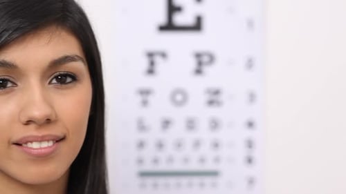 Smiling Woman Putting On Glasses at Eye Exam