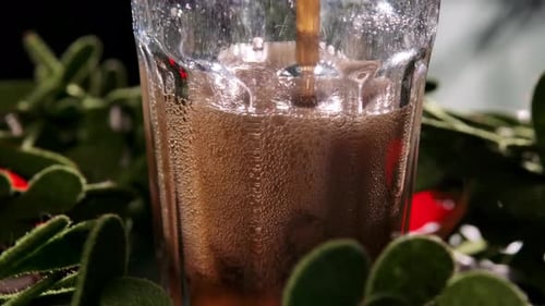Rotating Transparent Glass with Dark Sweet Liquid and Leaping Bubbles. Beautiful