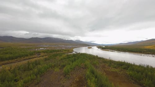 A drone soars above a vast expanse of greenery, showcasing a beautiful river that meanders through u