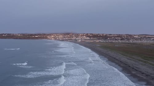 Dawn aerial along Tramore Strand toward seaside coast town in Ireland